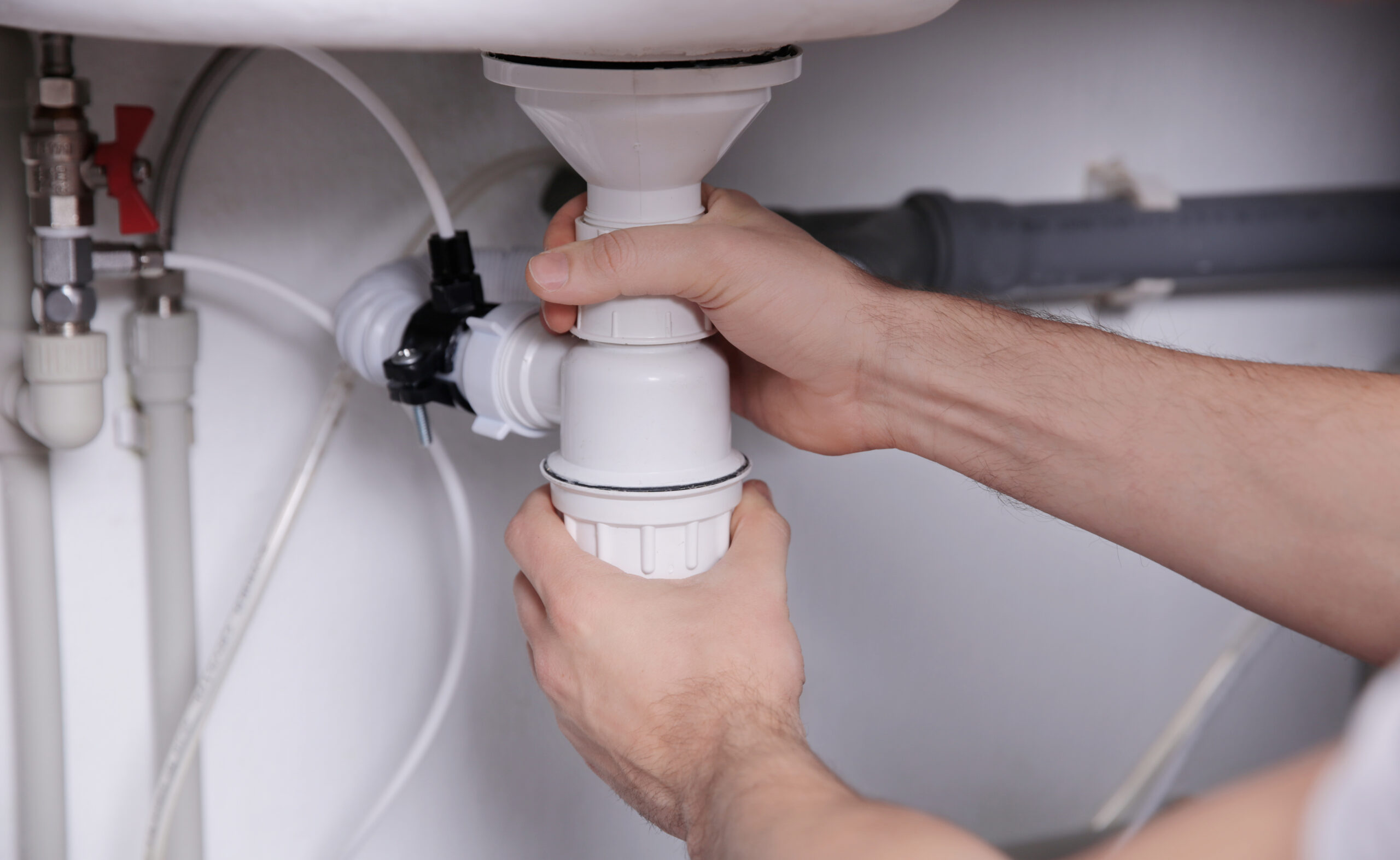 Plumber repairing sink pipes in kitchen, closeup